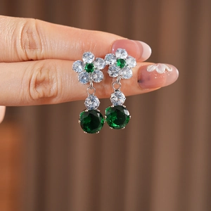 Macro shot of silver flower earrings with emerald green zircon and polished crystals