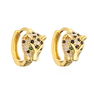 Macro shot of gold-plated leopard head earrings with zircon paving and green gemstones