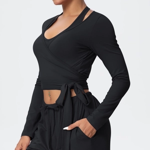 Detail of black sports yoga set featuring a cross-wrap long sleeve top with side bow tie