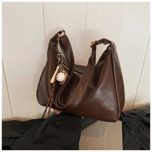 Detail of dark brown leather tote bag with baseball pendant and retro hardware