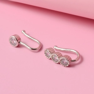 Detail of two silver ear cuffs featuring single and triple cubic zirconia stones