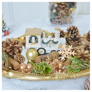 Detail of Christmas white train model and pine cones on a golden tray decor