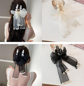 Detail of beige and black mesh bow hair claws with pearl embellishments in use