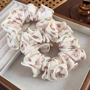Close-up of cream floral scrunchies with pink flower patterns in a wooden tray