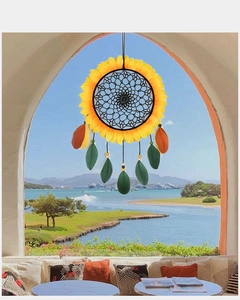 Sunflower dream catcher with orange feathers hanging in front of a coastal resort beach