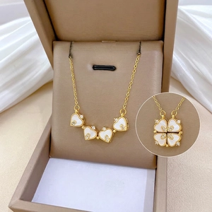 Collier trèfle cœur en titane doré avec nacre et cristaux dans un écrin à bijoux