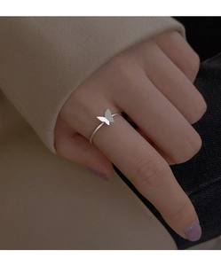 Dettaglio di un anello a farfalla in argento minimalista indossato sull'indice della mano