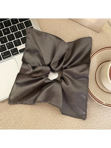 Detail of charcoal grey pleated fabric scrunchie with leather texture on office desk