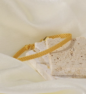 Detail of gold S925 silver woven mesh bracelet with lobster clasp on stone