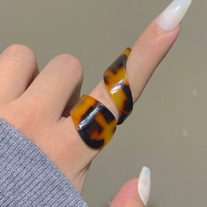 Detail view of acrylic tortoiseshell spiral ring with amber textures on finger