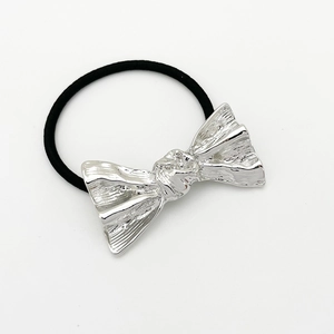 Detail of elegant silver alloy bow ornament with black elastic hair tie on white background