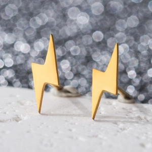 Macro view of gold stainless steel lightning bolt earrings on white stone base
