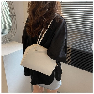 Side view of a minimalist white shoulder tote bag worn by a model in modern setting
