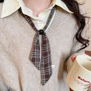 Close-up of vintage brown plaid chiffon scarf necklace with black buckle on a beige sweater