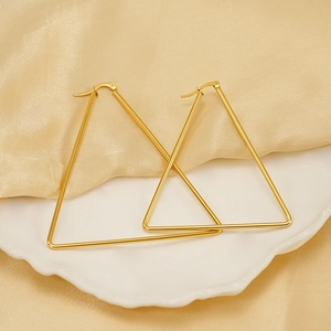 Minimalist geometric gold triangle hoop earrings displayed on a white ceramic plate