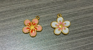 Detailed macro of gold-plated stainless steel flower pendants with pink and white enamel