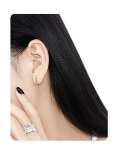 Detail shot of textured sterling silver geometric ring and hoop earring on a model