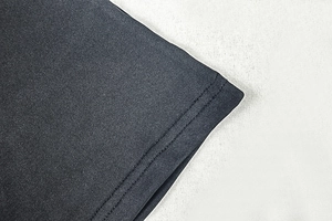 Detailed close-up of double-stitched hem and fine knit fabric on dark grey dress