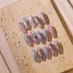 Nahaufnahme von blau-violetten Nagelstickern mit goldenen Sternzeichen und Perlenbesatz