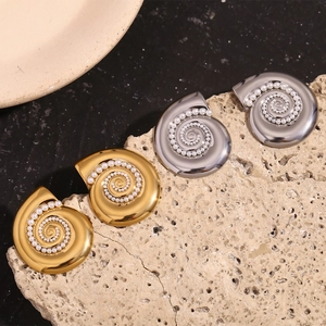 Detail of 18K gold plated conch shell earrings with pearls on a textured rock