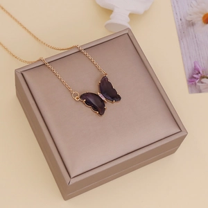 Close-up of a purple glass butterfly pendant with a gold chain on a premium gift box