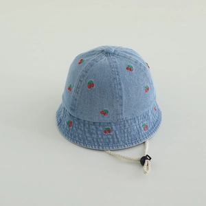 Detail of light blue denim bucket hat featuring embroidered cherries and adjustable chin strap