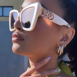 White cat eye sunglasses with gold chain temples and matching gold hoop earrings