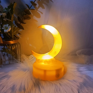 Macro view of a crescent moon night light emitting warm yellow glow on a plush white mat
