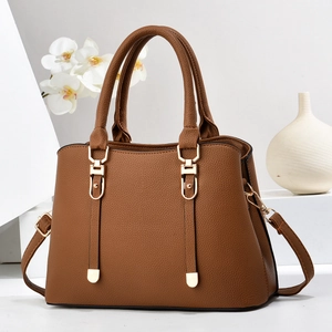 Classic brown pebbled leather women handbag with gold hardware on a minimalist display