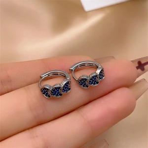 Close-up of silver earrings with three pavé-set blue zircon hearts on the hand