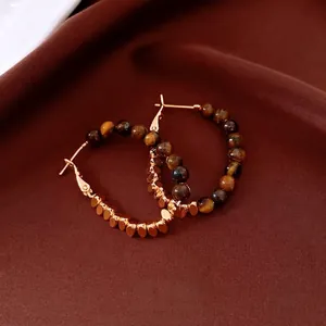 Vintage 18k gold plated hoop earrings featuring tiger eye beads on brown fabric background