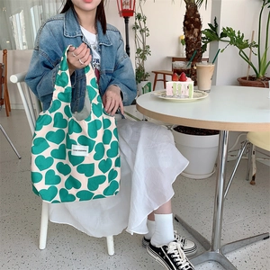 Detail of white corduroy tote bag with green heart patterns and LOVE label