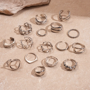 15-piece silver minimalist geometric open rings set on a textured beige stone surface