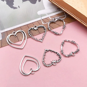 Detail of silver alloy heart pendants in minimalist hollow designs for jewelry making