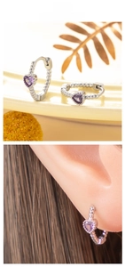 Detail of silver heart hoop earrings featuring purple zircon stones and twisted metal texture