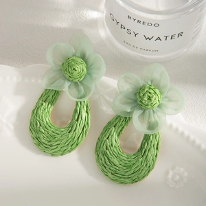 Detailed shot of green tulle flower earrings with hand-woven raffia teardrop rings