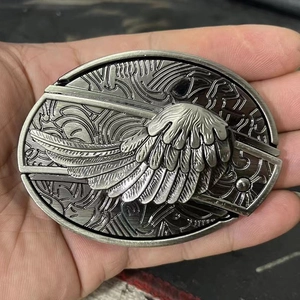 Detailed close-up of oval belt buckle with antique silver wings relief carving