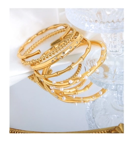 Close-up of gold titanium steel bracelets with bamboo texture and pearl details on mirror
