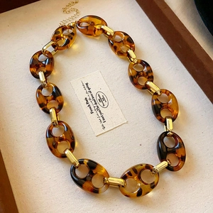 Detail of tortoise shell resin chain necklace with golden metal links on a tray