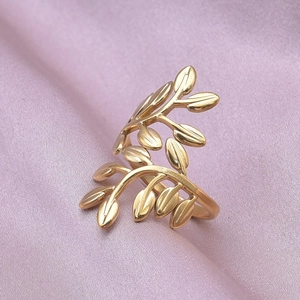 Macro shot of gold leaf-shaped ring on purple silk fabric focusing on delicate textures