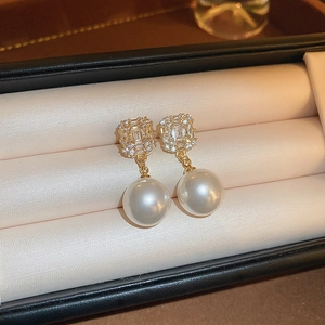 Gros plan de boucles d'oreilles dorées carrées avec zircons et perles blanches