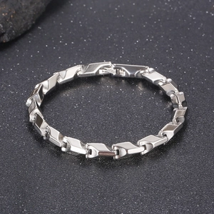 Detail view of silver stainless steel dragon bone chain bracelet on dark textured background
