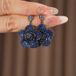 Detailed close-up of vintage-style blue rose earrings with zircon stones and dark metal