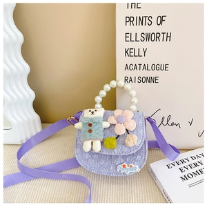 Detail of purple jacquard kids bag with pearl handle and cute teddy bear doll decoration