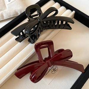 Detail of glossy black and wine red bow hair claws displayed on a jewelry tray