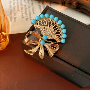 Vintage gold fan-shaped bow brooch with sky blue beads and sparkling white rhinestones