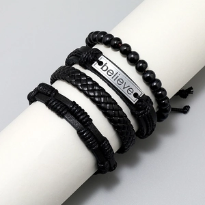 Detail of 4pcs black braided leather bracelet set featuring believe metal plate engraving