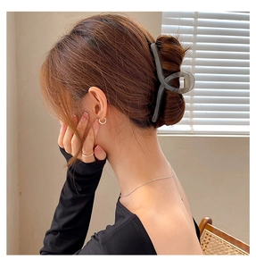 Detail of large grey translucent shark hair clip styled on a woman's bun hairstyle