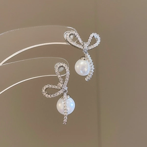 Detail showing bow-knot earrings with shimmering cubic zirconia and round pearl drops
