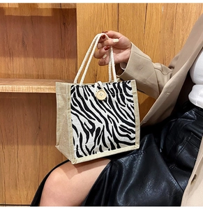 Detail of zebra print canvas handbag with a wooden button closure and woven handle